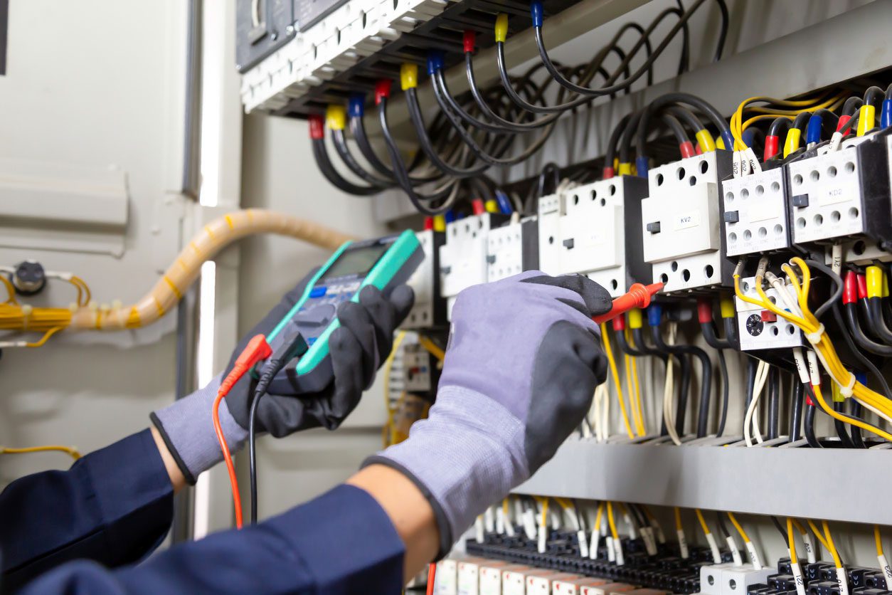 A person is working on electrical equipment