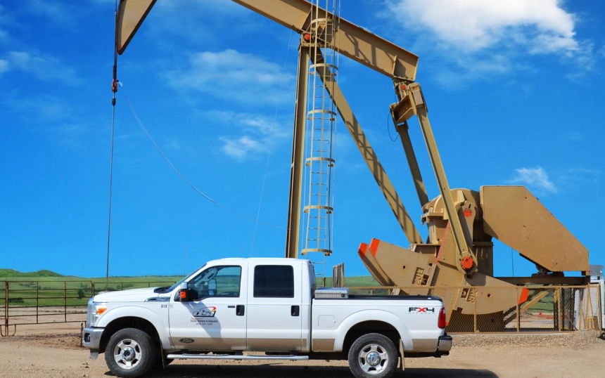 A white truck parked in front of an oil rig.