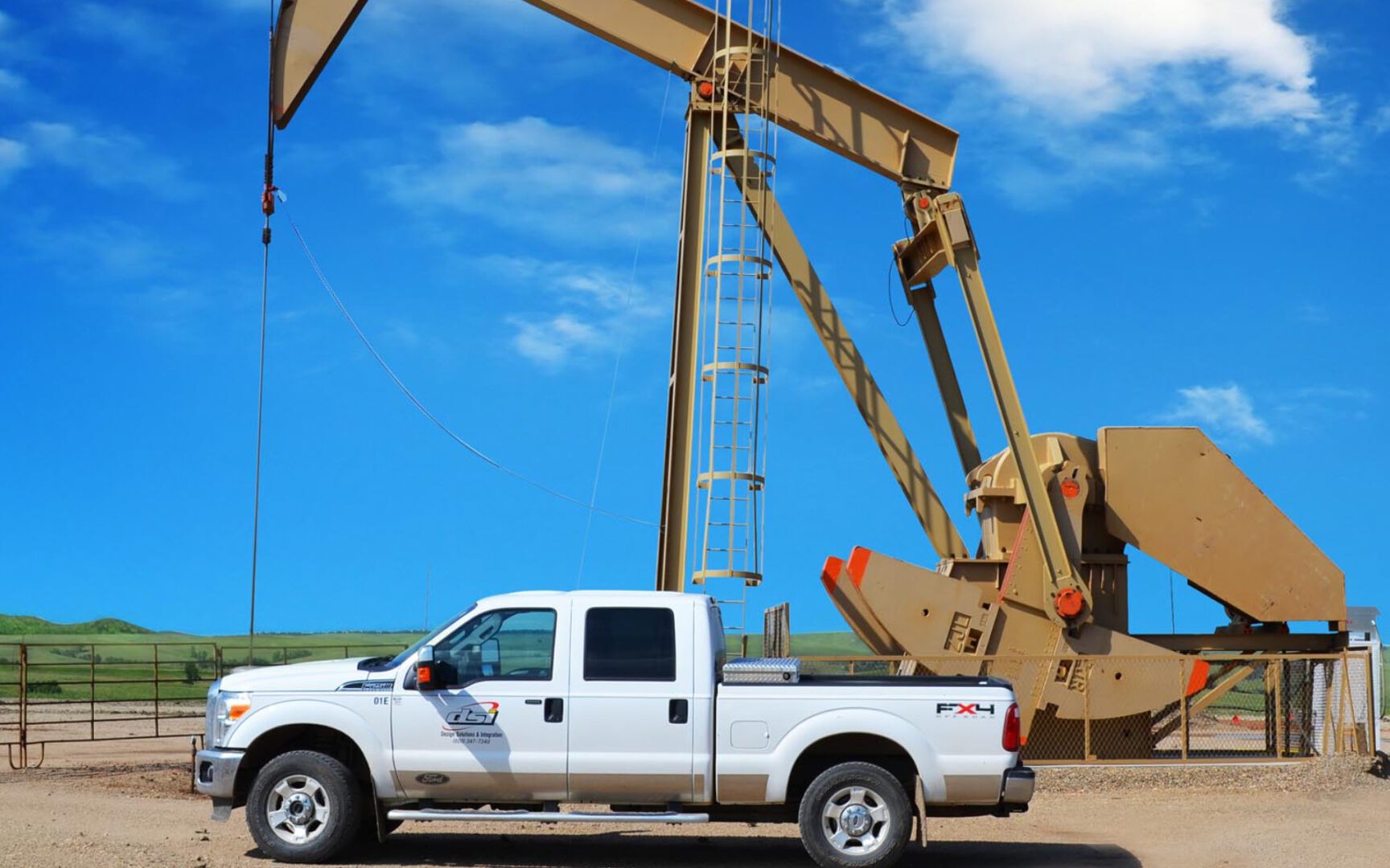 A white truck parked in front of an oil well.