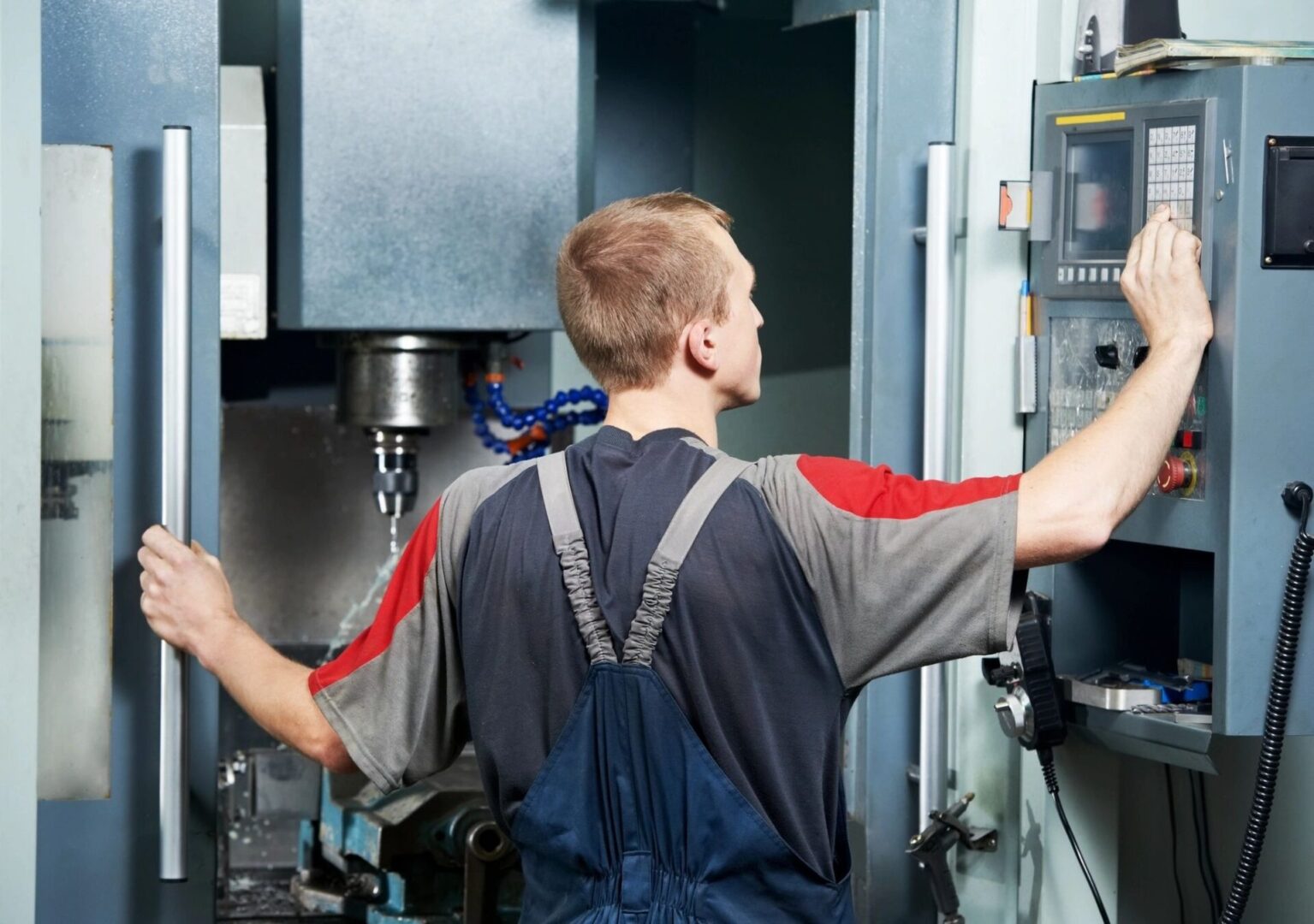 A man in blue overalls is working on a machine