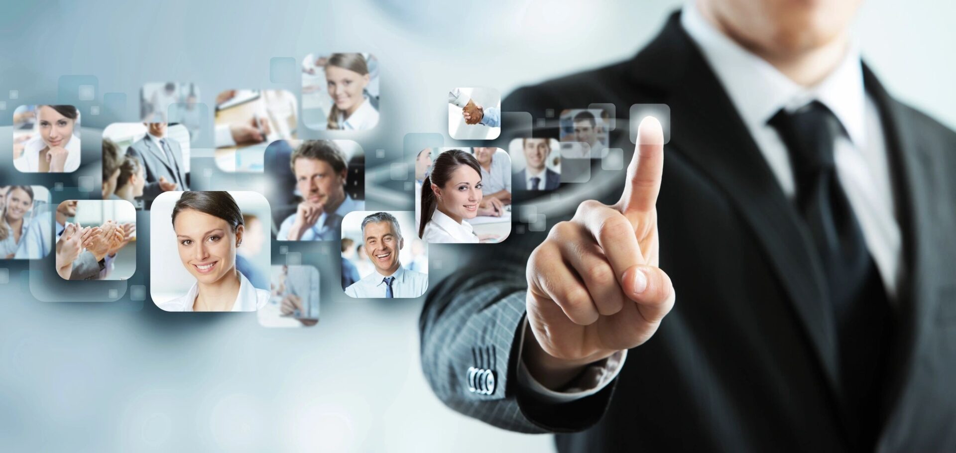 A man in a suit pointing to several pictures of people.