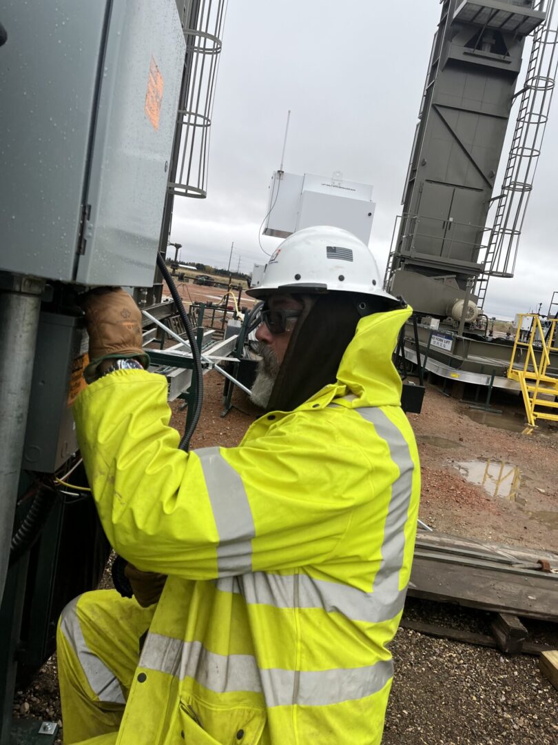 DSI field technician working on an enclosure at a wellsite in wet weather