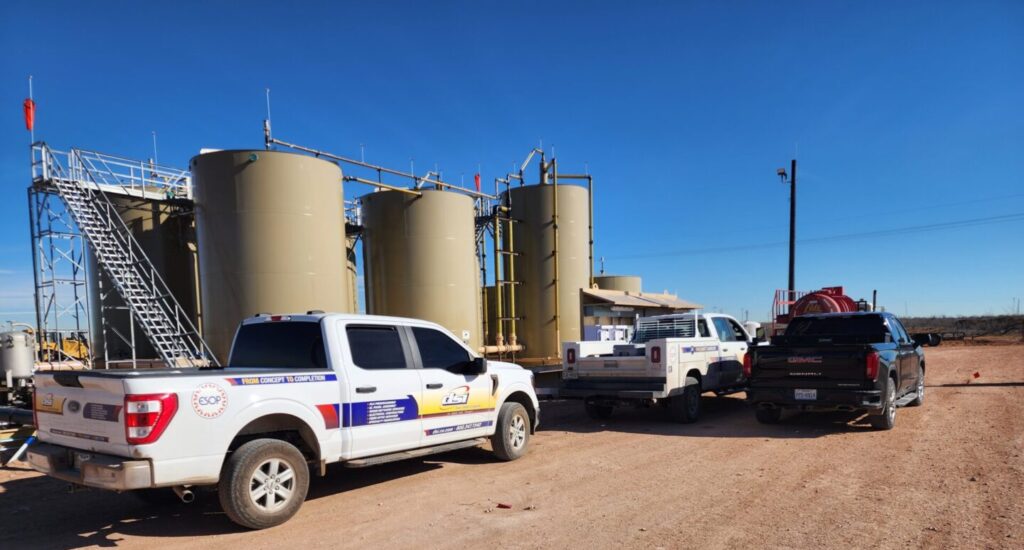 Multi-well oil and gas facility with field equipment and production tanks in operation