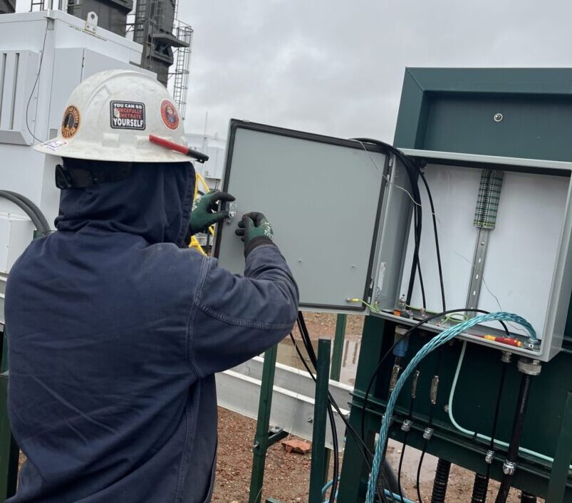 DSI technician in PPE performing field automation and control integration at an oil and gas site