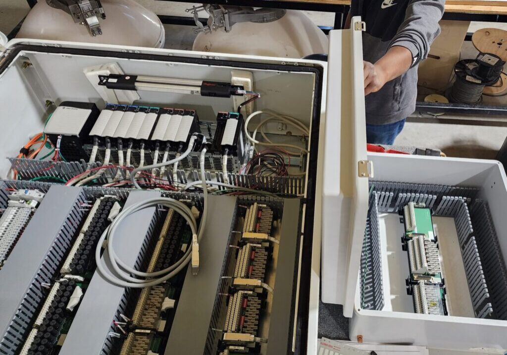 DSI technician working on open PLC control panels in the shop, with terminal blocks and automation modules visible